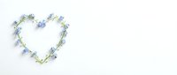 Heart-shaped wreath made of delicate blue flowers and green leaves on white background for romantic designs, wedding invitations, and spring decor.