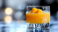 Orange cocktail with ice cubes in crystal glass on bar counter. Refreshing alcoholic drink with citrus garnish for bartending and mixology concepts.