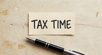 Tax time reminder note with black pen on wooden desk for accounting and financial planning preparation during filing season.