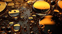 Golden water drops on dark surface create abstract macro photography with reflective spheres and dramatic lighting effects for luxury backgrounds.