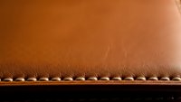 Brown leather material with decorative stitching detail showing craftsmanship texture for luxury goods manufacturing and artisan leatherwork projects.