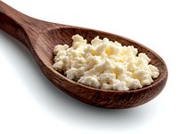 Fresh cottage cheese in wooden spoon isolated on white background. Natural dairy product with soft texture and creamy white color. Healthy protein food.