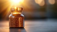 Small glass jar with golden spice or seasoning powder illuminated by warm sunset light on wooden surface, creating atmospheric culinary scene.