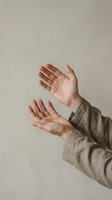 Open hands reaching upward in prayer or meditation gesture against neutral beige background for wellness and spirituality concepts.