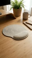 Ergonomic mouse pad with wrist support on wooden desk workspace with plant, coffee mug and notebook for comfortable computer use and office productivity.