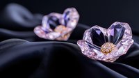Delicate pink crystal flowers with golden centers rest on flowing black silk fabric, creating elegant jewelry or decorative elements for luxury designs.