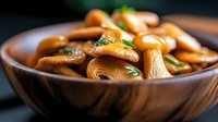 Fresh sliced mushrooms sauteed with herbs in wooden bowl, close up view with selective focus. Delicious vegetarian cuisine for restaurant menu.