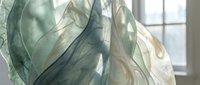 Flowing translucent green fabric with soft natural lighting creates elegant movement and texture for fashion or interior design projects.