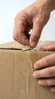 Male hands opening cardboard box with twine, isolated on white background. Suitable for shipping, delivery, logistics, unboxing, and business concepts.