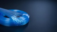 Blue fiber optic cable bundle with glowing light transmission on dark background for telecommunications and high-speed internet technology applications.