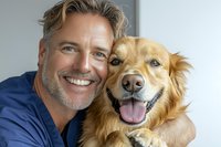 Mature man with gray hair and blue shirt embracing happy golden retriever dog showing genuine joy and companionship, perfect for pet care advertising.