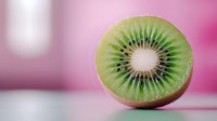 Fresh juicy kiwi slice showing detailed texture and seeds on pink blurred background, macro food photography with selective focus for healthy eating concept.