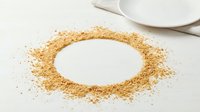 Golden glitter arranged in oval frame on white surface with ceramic plate, suitable for festive designs, invitations, and decorative backgrounds.