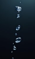 Water droplets of varying sizes suspended in mid-air against a dark background, capturing the fluid dynamics and refraction of light through liquid spheres for scientific and design applications.