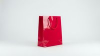 Bright red glossy shopping bag with handles isolated on white background, ready for retail, e-commerce, and packaging design projects.