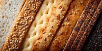 Assorted bread slices showing variety of textures and toppings including sesame seeds, poppy seeds, and classic white bread arranged in rows.