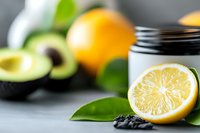 Fresh citrus lemon half with green leaves, orange and avocado in background on light gray surface, selective focus food photography composition.