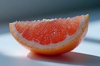 Fresh juicy grapefruit slice with visible pulp segments and crystalline texture on smooth surface in soft natural lighting, macro food photography.