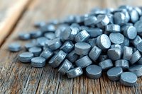 Activated charcoal tablets scattered on rustic wooden surface for natural health and detox supplements.
