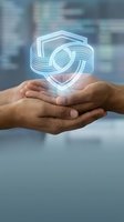 Hands holding glowing digital shield symbol representing cybersecurity protection and data safety in modern business environment.