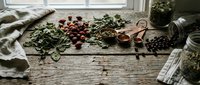 Rustic wooden table with fresh herbs, berries and natural ingredients for cooking and food preparation in cozy kitchen setting.