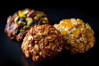 Artisanal oatmeal cookies with nuts, dried fruits and seeds on dark background. Close up macro shot shows rich texture and natural ingredients. Food photography.