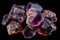 Raw fluorite crystal specimens in purple, orange and clear variations on black background showing natural mineral formation and crystalline structure.