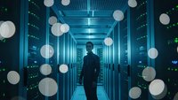 Male IT professional walking through modern data center server room with glowing blue lights and network connectivity visualization overlay.