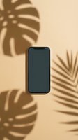 Smartphone with blank dark screen displayed on warm beige background with tropical plant shadows for app mockup and digital marketing use.