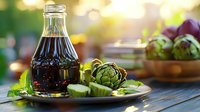 Fresh artichokes and balsamic vinegar dressing on rustic wooden table with blurred garden background, natural sunlight creates warm atmosphere.