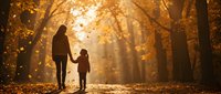 Mother and child walking hand in hand through golden autumn forest with sunlight streaming through trees and falling leaves creating warm atmospheric scene.
