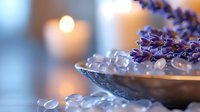 Healing rose quartz crystals and lavender sprigs in vintage silver bowl with glowing candle creating peaceful spa atmosphere for meditation and wellness practices.