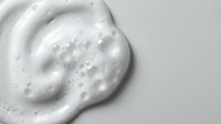 White creamy foam texture with bubbles on clean background for skincare cosmetic product design and beauty applications.