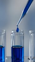 Laboratory pipette dropping blue liquid into test tube for scientific research and chemical analysis experiments.