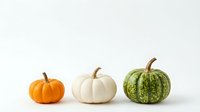 Three decorative pumpkins in orange, white and green colors arranged on clean white background for autumn seasonal design and harvest decoration.
