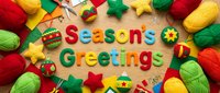 Seasons Greetings text surrounded by colorful felt ornaments, yarn balls, and craft supplies on wooden table, festive holiday DIY flat lay.
