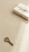 Stack of cream envelopes tied with twine and vintage key on neutral beige textured background, suitable for stationery, correspondence, and business design projects.