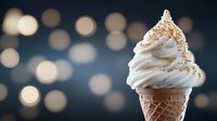 Soft serve vanilla ice cream cone with sprinkles against blurred bokeh lights background, creamy swirled dessert with golden toppings creates dreamy atmosphere.