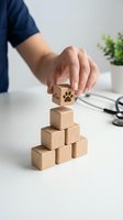 Hand placing wooden cube with paw print on pyramid of blocks representing pet care services growth and veterinary business development concepts.