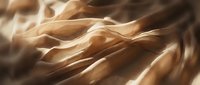 Silky golden fabric with flowing waves and soft light reflections, creating an elegant textile background for luxury design projects.