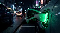 Electric car charging at night on city street with green glowing cable and urban lights creating sustainable transportation concept for eco-friendly mobility.