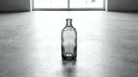 Empty glass bottle on concrete floor in industrial space with windows, suitable for beverage, recycling, and minimalist design projects.