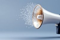 White megaphone emitting glowing particles and sparkles against blue background, creating magical communication effect for marketing and announcement concepts.