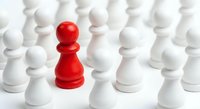 Red chess pawn standing out among white pawns on white background. Leadership, uniqueness, strategy and business concept for presentations.