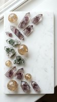 Collection of healing crystals and gemstones arranged on white marble surface including amethyst points, citrine spheres and green fluorite specimens.
