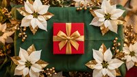 Red gift box with gold ribbon surrounded by white poinsettias and golden berries on green fabric, festive Christmas holiday flat lay.