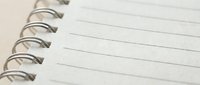 Close-up of blank lined spiral notebook page with metal wire binding, clean white paper ready for writing, note-taking, journaling or creative projects.