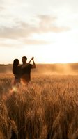 Romantic couple dancing in golden wheat field at sunset with warm light and soft focus creating dreamy atmosphere for love and relationship concepts.