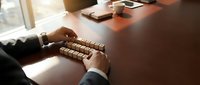 Businessman arranging wooden letter cubes on a desk near a window, symbolizing strategy, planning, and business communication concepts.