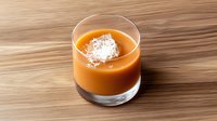 Creamy butterscotch dessert topped with coconut flakes served in elegant glass on wooden surface. Rich caramel-colored pudding creates luxurious dining experience.
